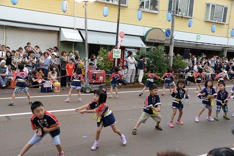 道路でソーラン節を踊る法被を着た子供たちの写真