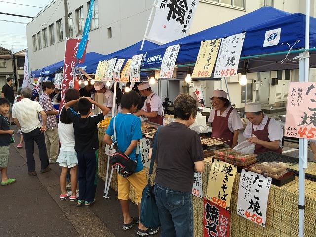 焼きそばやたこ焼きが並ぶマルシェに人が集まっている写真