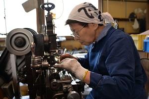 手元で機械を操作する女性の写真