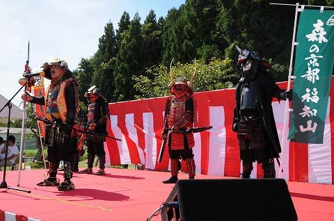 屋外の舞台上で甲冑を着て武士のコスプレをした男性たちの写真