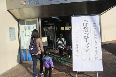 「つばめ歯っぴ―フェア2016」と書かれた白い看板が立てられた建物の入口付近にいる2組の親子の写真