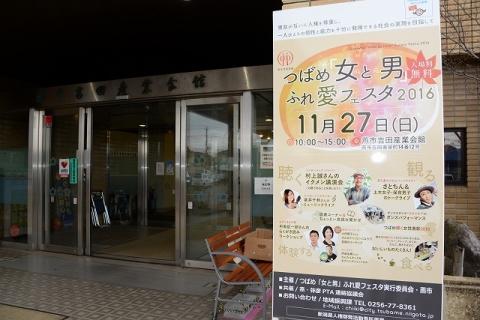 「つばめ「女(ひと)と男(ひと)」ふれ愛フェスタ2016」と書かれた看板と看板のそばにある吉田産業会館の入り口の写真