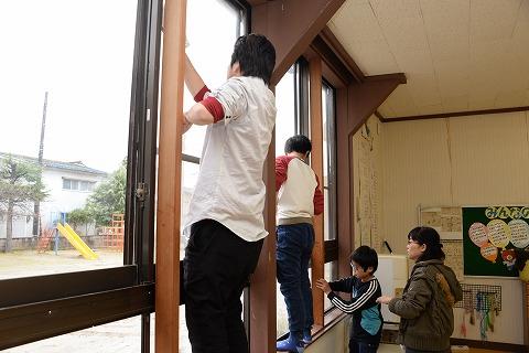 窓のサッシ部分にのぼってふき掃除をしている男性と子供の写真