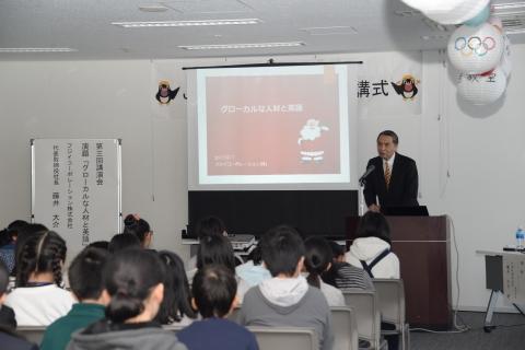 前に立って講演をする藤井大介氏とその話を聞く受講生の子どもたちの写真