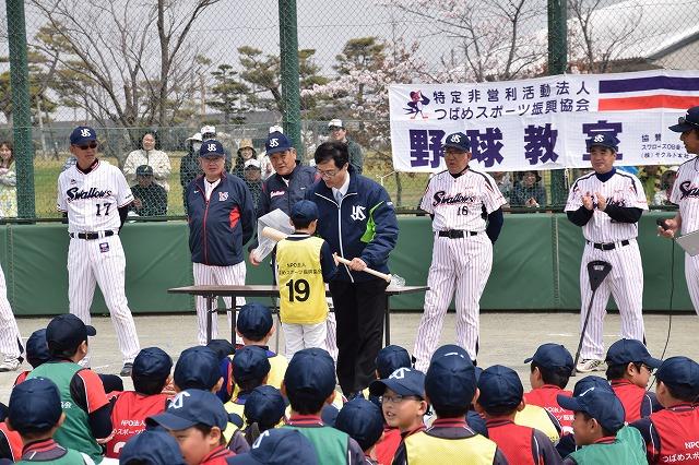 野球教室と書かれた横断幕のあるグラウンドで大人と児童が集まっている写真