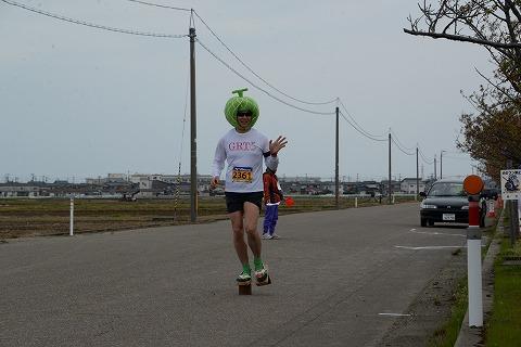 緑色の被り物をして走るマラソン大会参加者の写真