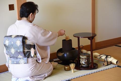 着物を着た女性が正座で座ってお茶を入れている写真