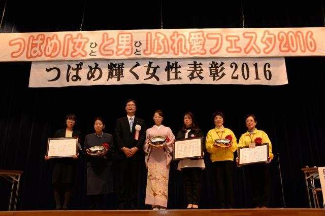 「つばめ輝く女性表彰2016」の横断幕の下に立つ男女7人の写真