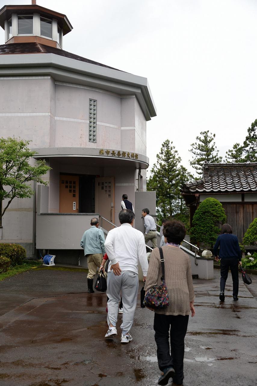 コンクリート製の小さい建物「史料館」に移動する参加者たちの写真