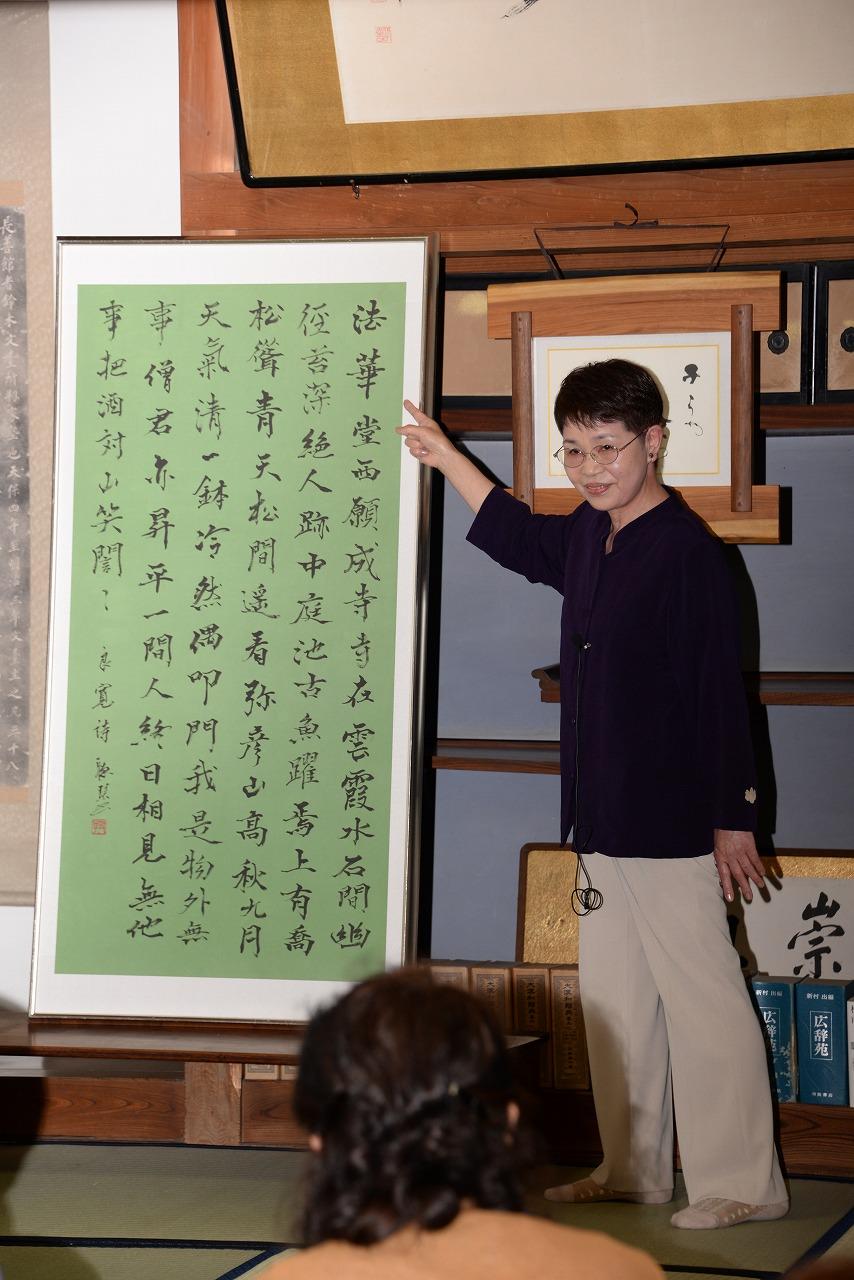 前に立ち、緑色の資料に指をさしながら昔話をする吉田おはなしの会の女性会員の写真