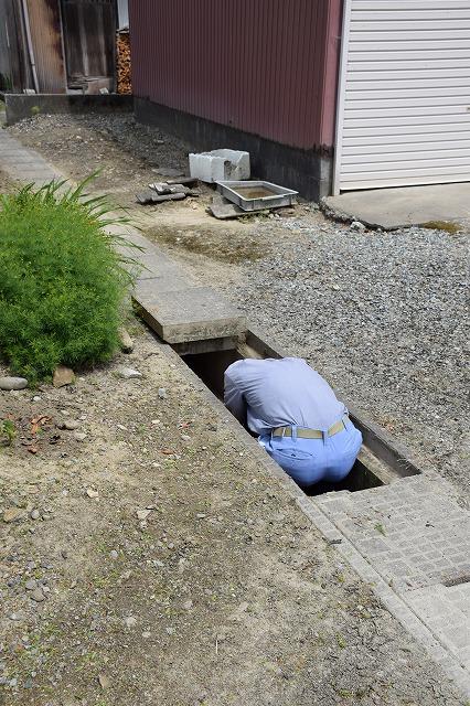 人1人が入れる小さい用水路に体を埋めて頭部を守っている男性住民の写真