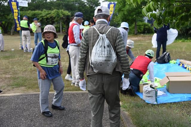避難訓練に参加した非常持ち出し袋を背負った年配の男性の後ろ姿の写真