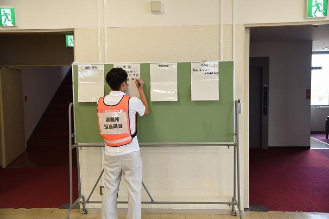 避難所担当職員が防災対策に必要な4つの項目をボードに記入しながら説明している様子の写真