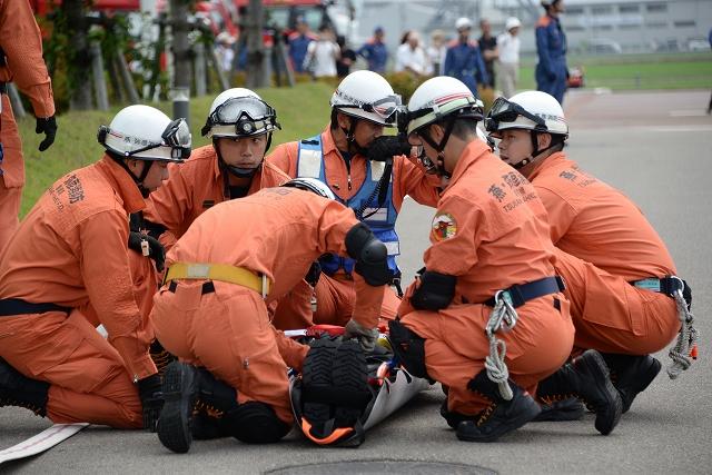赤い服を着て救護訓練を行なう消防隊の人々の写真