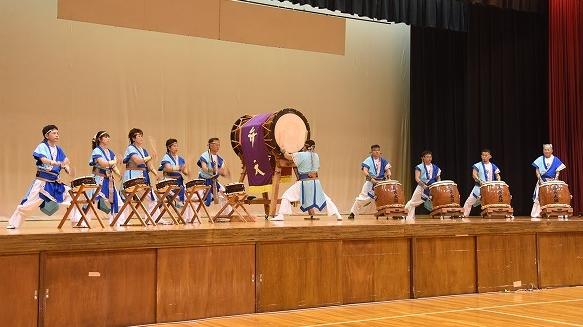 「弁天」と書かれた大きな太鼓を中心に水色を基調とした青色の民族衣装を纏ったチームによる響演の様子を写した写真