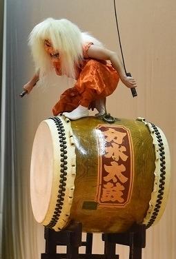 鬼に扮した奏者が豪快に太鼓の上に飛び乗りポーズを決めている処の写真