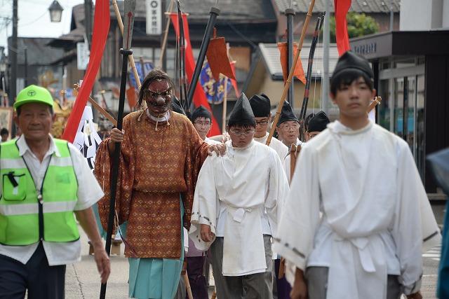 天狗に率いられて吉田諏訪神社へ行脚する白い神事服の人たちの写真