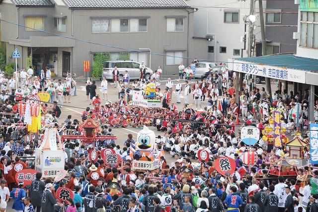 子ども達の手で、色々なキャラクターが乗せられた神輿と参列者で大賑わいな会場の写真