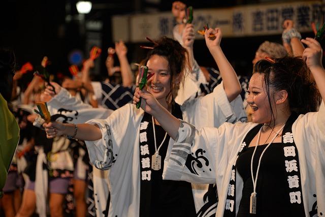 白を基調とした「吉田浜首町」のはっぴを着て踊る2人女性と周りで踊る人々の写真
