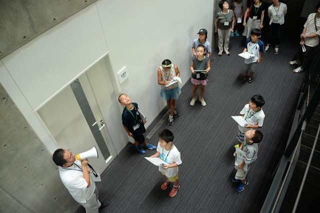 廊下で市役所職員の説明を聞く子どもたちの写真
