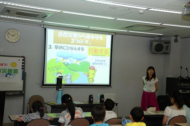 「自然災害のからみを守る方法」をスライドで説明する菊池さんと鑑賞する子供たちの写真