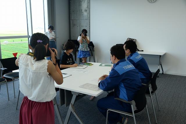 防災課の職員にインタビューしている姿をカメラで撮影している子供たちの写真