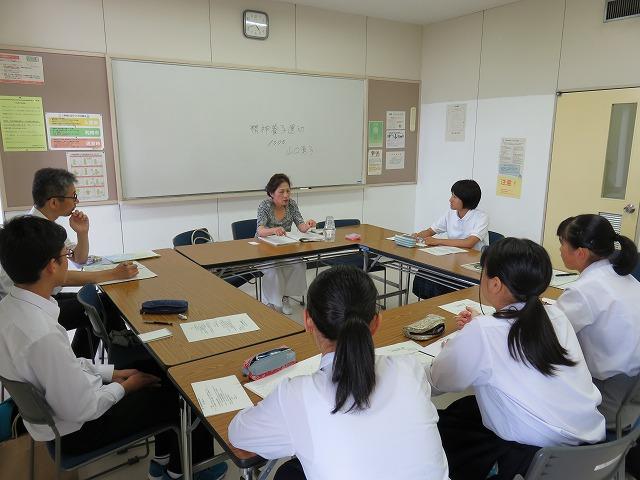 教室で女性の話を聞いている生徒たちの写真