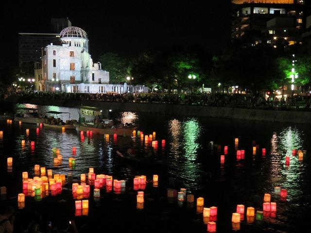 夜の原爆ドームを背に大田川を流れている無数の灯篭の写真