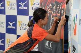 和田麻希選手がタペストリーにサインしている処の写した写真