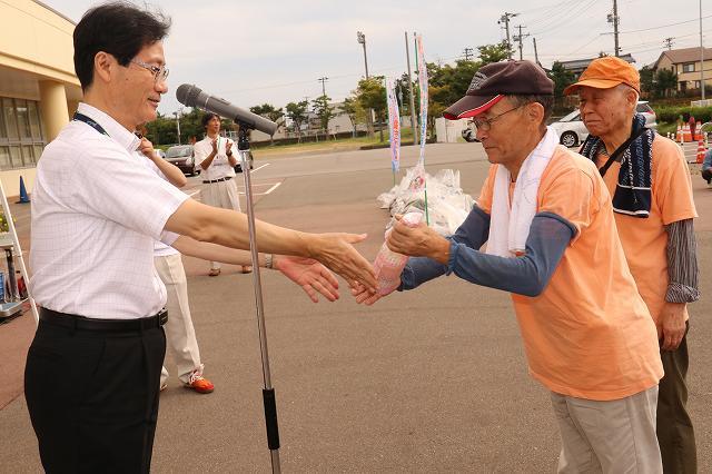 商品を手渡す市長と、それを受け取るジャンケン大会勝者の帽子を被った男性の写真