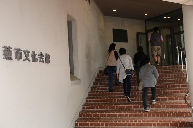 茶色い階段を上り、燕市文化会館の建物に入っていく人たちの写真