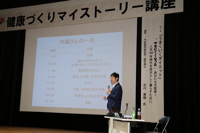 スライドに映し出された「内藤さんの1日」について説明する先生の写真