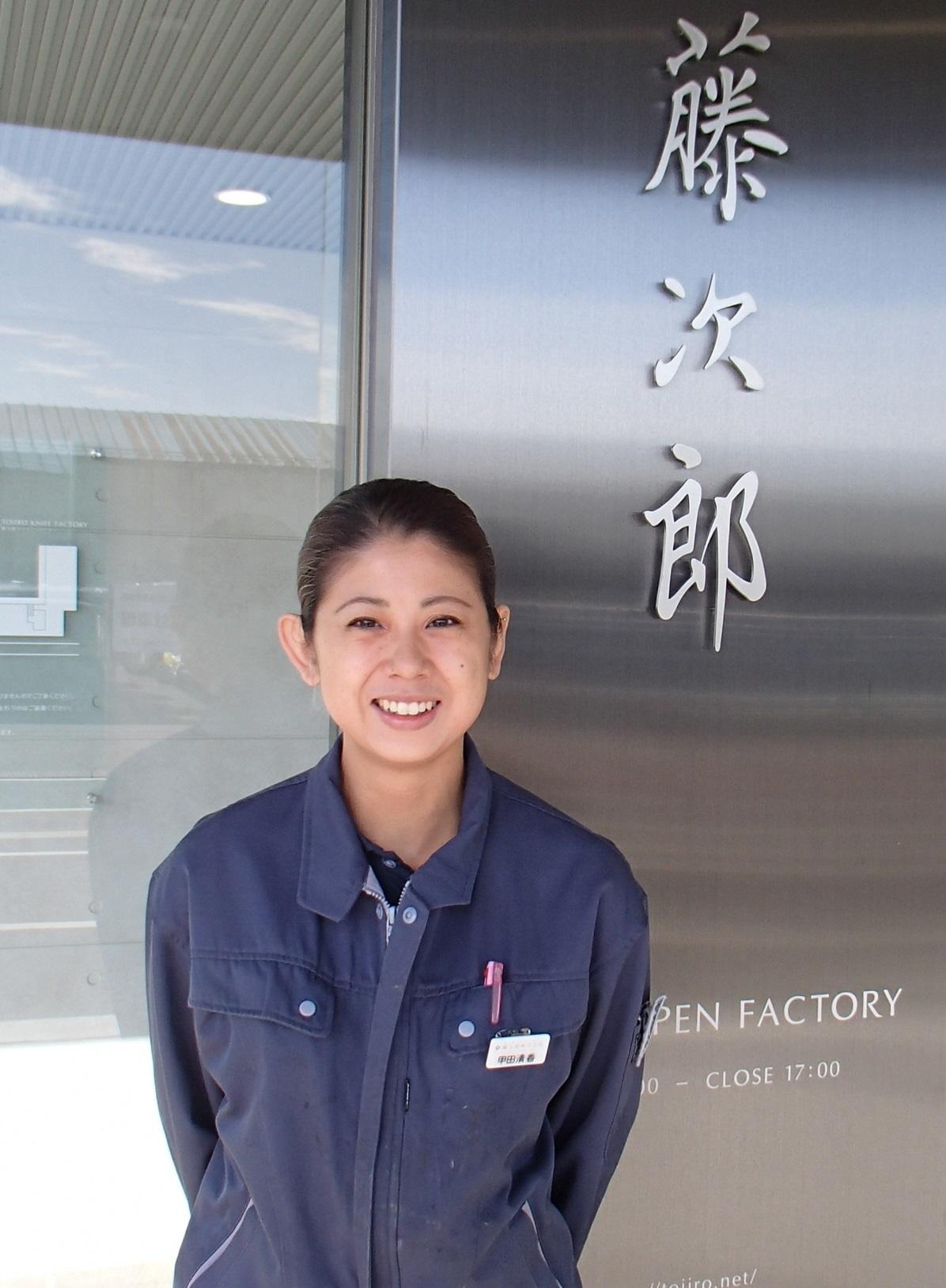 藤次郎株式会社オープンファクトリー入口を背景に笑みを浮かべて立っている女性の写真