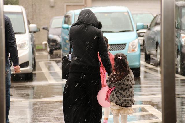 横殴りの雪のなか、外へ出ようとしている母娘の様子の写真
