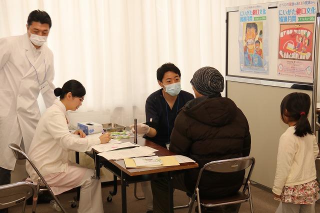 歯医者さんがニット帽をかぶった男性参加者の検診をしている様子の写真