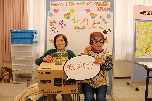 当選した景品のトースターを抱えて椅子に座っている女性2人の写真
