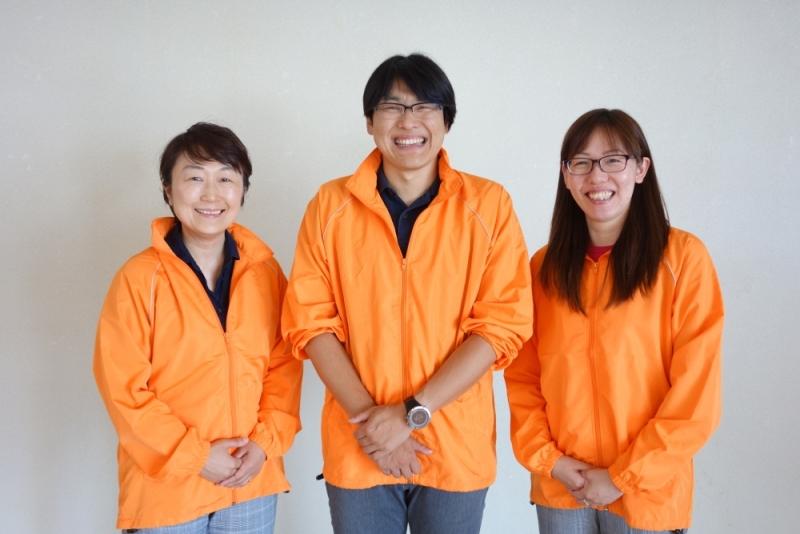 オレンジのウェアを着た3人の人々の写真
