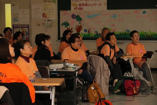 おそろいの薄いオレンジのTシャツを着て、同じ方向に注視している参加者たちの写真