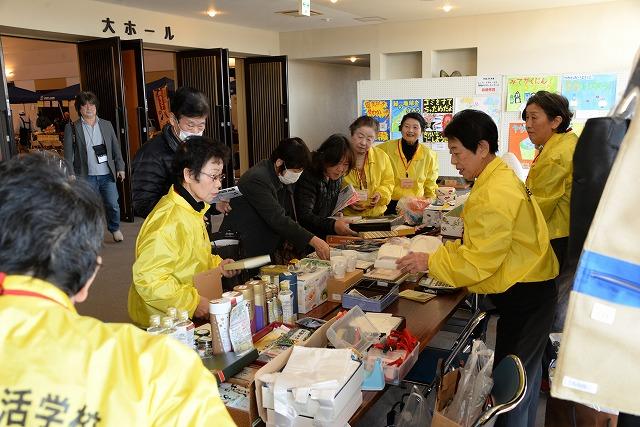 テーブルにたくさんの商品を並べている黄色い上着をきた「つばめ生活学校」の職員たちの写真