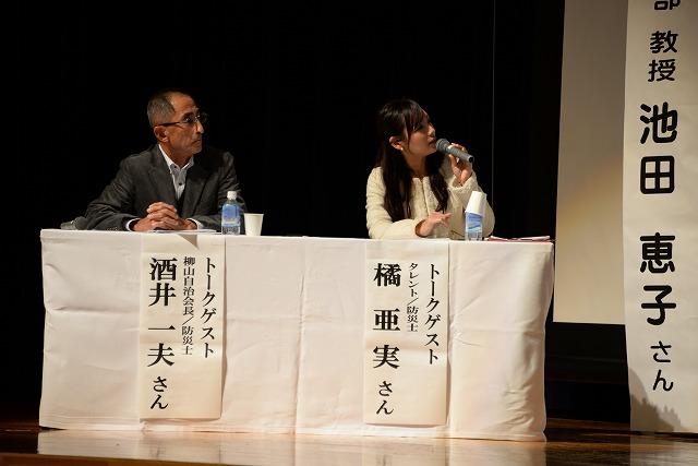 壇上の白い机で並んでトークセッションを行う橘亜実さんと酒井一夫さんの写真