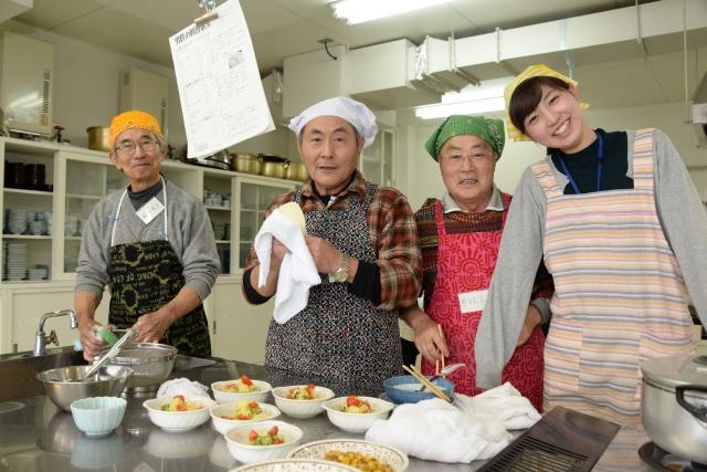 調理した料理を盛り付けした3人の男性と女性職員が並んだ記念写真
