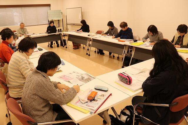 会議室にて白い長テーブルで囲い研修を行っている「七色の会」のボランティア活動をしている人たちの写真