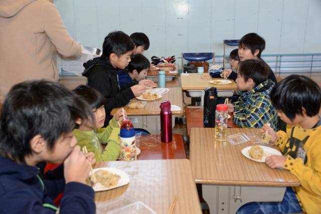 生徒たちが机を並べて全員でおこわ団子を食べている様子の写真