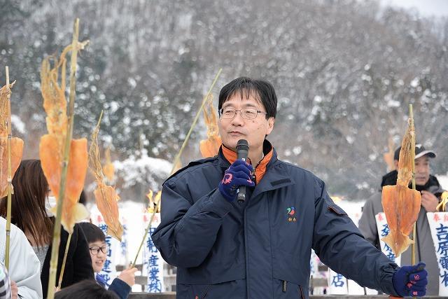 先端にスルメを吊るした棒を持ち挨拶をする鈴木市長の写真