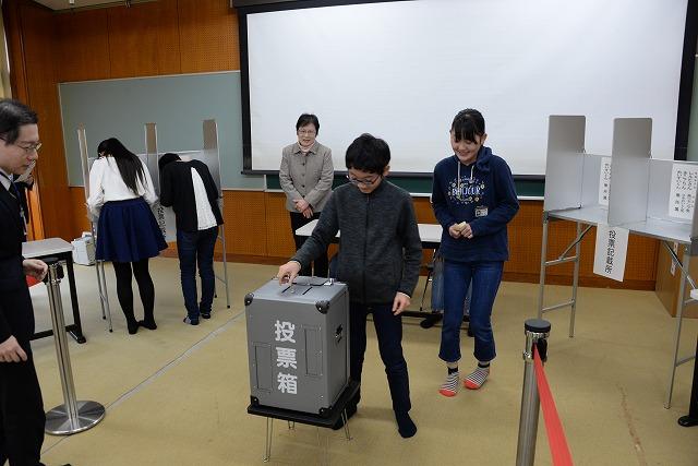 本物の投票箱に実際に投票する男子生徒の写真