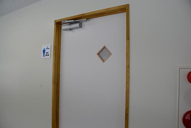 男性のピクトグラムに男子更衣室と書かれたプレートとその部屋のドアの写真