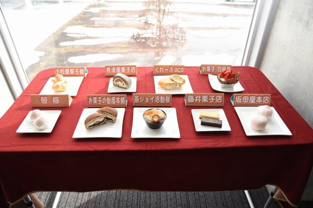 テーブルに並べられた市内9つのお菓子屋と団体でエントリーした9種類のスイーツの写真