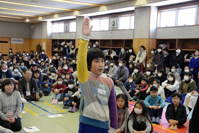午後の小学校中高学年の部で手を上げマイクの前で選手宣誓をする男の子の写真
