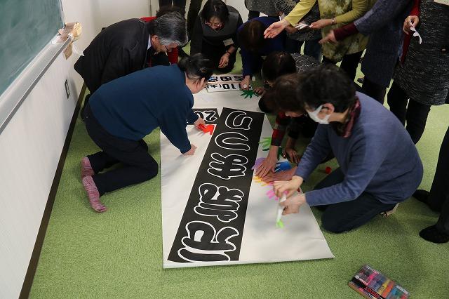 「元気まつり」と書かれた大看板に自分で作った紙の手形を貼り始める参加者たちの写真
