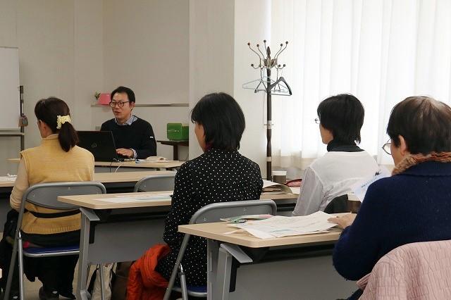 講演する池田兼一さんと資料を見ながら講演を聞いている参加者たちの写真
